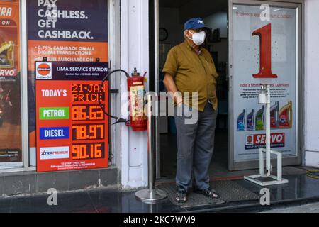 An einer Tankstelle in Kalkutta steht ein Mann mit Maske neben einer Tafel, auf der neue Preise für verschiedene Brennstoffe angezeigt werden. Die Benzinpreise in Kalkutta erreichen nach dem Anstieg der Rohölpreise im Land einen neuen Höhepunkt (Foto: Debarchan Chatterjee/NurPhoto) Stockfoto