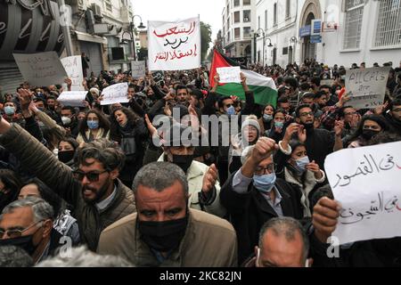 Demonstranten heben ein Plakat auf, auf dem auf Arabisch steht: ‘Die Menschen wollen den Sturz des Regimes’, während sie während einer Demonstration in der Hauptstadt Tunis die Waffen erheben und regierungsfeindliche Parolen skandieren, um gegen die „Polizeigewalt“ zu protestieren, die während der letzten nächtlichen Proteste im Land eingesetzt wurde. Sie forderten die Freilassung der jungen Demonstranten, die von der Polizei verhaftet wurden. Demonstranten haben auch gegen die Erklärung des Präsidenten des Shura-Rates der islamistischen Ennahdha-Partei Tunesiens, Abdelkarim Harouni, protestiert, der sagte: „Die Kinder von Ennahdha werden vor Ort sein Stockfoto