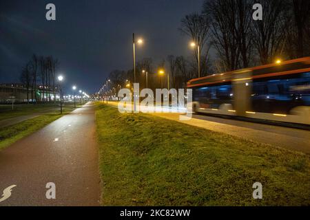 Ein leerer Bus auf der Busspur bewegt sich. Fast verlassene Straße, wie sie in einem Markt- und Wohngebiet in der Nähe der niederländischen Stadt Eindhoven zu sehen ist, während die erste Ausgangssperre nach dem Zweiten Weltkrieg verhängt wurde. Einschränkungen gelten zwischen 21:00 und 04:30 Uhr Ortszeit. Bürger können ihre Häuser nur aus triftigen Gründen wie Gesundheitsprobleme, Arbeit oder Reisen verlassen. Die Geschäfte änderten auch ihre Arbeitszeit, während die nicht wichtigen Geschäfte und Märkte seit Dezember geschlossen sind. Die Regierung hat die Entscheidung für die Sperrung und die Einschränkung der Freizügigkeit getroffen, um die Ausbreitung der neuen Stammmutation des Coronavirus Co zu bekämpfen Stockfoto