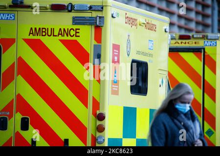 Eine Frau mit Gesichtsmaske geht am 25. Januar 2021 an Krankenwagen vor der Notaufnahme des Royal London Hospital in London, England, vorbei. In ganz Großbritannien werden die Todesfälle, die innerhalb von 28 Tagen nach einem positiven Covid-19-Test verzeichnet wurden, diese Woche auf über 100.000 steigen, wobei der aktuelle Wert bei 98.531 liegt. In London und den meisten anderen Regionen Englands scheinen die Coronavirus-Raten jedoch zu sinken, so die heute berichteten Daten. (Foto von David Cliff/NurPhoto) Stockfoto