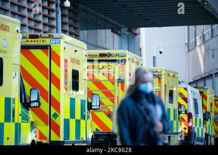 Eine Frau mit Gesichtsmaske geht am 25. Januar 2021 an Krankenwagen vor der Notaufnahme des Royal London Hospital in London, England, vorbei. In ganz Großbritannien werden die Todesfälle, die innerhalb von 28 Tagen nach einem positiven Covid-19-Test verzeichnet wurden, diese Woche auf über 100.000 steigen, wobei der aktuelle Wert bei 98.531 liegt. In London und den meisten anderen Regionen Englands scheinen die Coronavirus-Raten jedoch zu sinken, so die heute berichteten Daten. (Foto von David Cliff/NurPhoto) Stockfoto