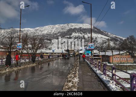 Am 25. Januar 2021 laufen die Menschen an einem sonnigen Tag, da die Berge nach dem Neuschnee in Baramulla, Jammu und Kashmir, Indien, mit Schnee bedeckt sind (Foto: Nasir Kachroo/NurPhoto) Stockfoto