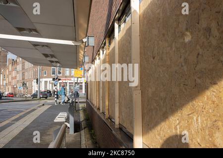 Vertäfelt mit Holzpaneelen zerbrochene Fenster. Die Folgen der Unruhen in Rotterdam gegen die Ausgangssperre. Beschädigte Fenster von Geschäften, Cafés, Fast-Food-Kette, zerstörter Bürgersteig, kaputte Geldautomaten, Bushaltestellen, Straßenbahnhaltestellen, beschädigte Fenster und Gläser sogar in einem Wohngebiet wurden durch die gewalttätigen Demonstranten verursacht, die mit der Polizei zusammenprallten und das Gebiet um Groene Hilledijk, Beijerlandselaan und Randweg plünderten. Es ist die 3. aufeinander folgende Nacht der Unruhen und Auseinandersetzungen mit den politischen Richtlinien, nachdem die Regierung die Ausgangssperre verhängt hat, um die Ausbreitung der Coronavirus-Pandemie Covid-19 und die neue Mutation zu bekämpfen, Stockfoto