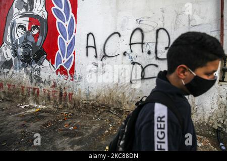 Ein Teenager geht vor eine Wand, auf der eine Zeichnung eines Mannes mit Gasmaske und das Wort ‘ACAB’ (ein Anti-Polizei-Slogan, der bedeutet: Alle Bullen sind Bastarde) graffiert sind, Im beliebten und harten Viertel Hay Ettadhamen, einer der bevölkerungsreichsten Städte Tunis, protestierte man während eines protestmarsches in Richtung der Stadt Bardo in Tunis gegen die Brutalität der Polizei, die Marginalisierung und die wirtschaftliche und soziale Krise im Land. Demonstranten hatten auch die Freilassung von Jugendlichen gefordert, die von der Polizei während der letzten nächtlichen Proteste verhaftet wurden, wo sie mit der sec zusammenprallten Stockfoto