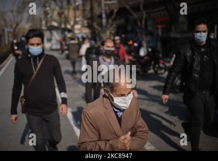 Ein älterer iranischer Mann mit einer schützenden Gesichtsmaske geht inmitten des COVID-19-Ausbruchs im Iran am 27. Januar 2021 entlang einer Straße in der Nähe des traditionellen Großen Basars von Teheran. (Foto von Morteza Nikoubazl/NurPhoto) Stockfoto