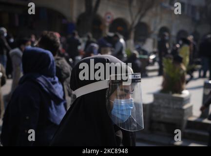 Eine verschleierte iranische Frau, die eine schützende Gesichtsmaske und einen Gesichtsschutz trägt, geht inmitten des COVID-19-Ausbruchs im Iran am 27. Januar 2021 entlang einer Straßenseite aus Teherans traditionellem Grand Basar. (Foto von Morteza Nikoubazl/NurPhoto) Stockfoto