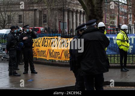 Polizeibeamte stehen neben einem Protestbanner, während die Polizei am 27. Januar 2021 in London, England, eine Operation zur Abstellung des Lagerplatzes ‘Stop HS2’ in den Euston Square Gardens durchgeführt hat. Trotz der Räumungen bleibt eine kleine Gruppe von Aktivisten in einem Tunnel, der heimlich unter dem Gelände errichtet wurde, um die nächste Phase der Arbeiten am Hochgeschwindigkeitsbahnprojekt zu verhindern, das London mit Birmingham, Manchester und Leeds verbinden soll. (Foto von Wiktor Szymanowicz/NurPhoto) Stockfoto