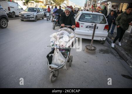 Ein älterer Mann schiebt einen Wagen in die Straße eines schwierigen Viertels der beliebten Stadt Ettadhamen, die eine der bevölkerungsreichsten Städte der Hauptstadt Tunis ist. Ettadhamen City, dessen Name „Solidarität“ bedeutet, wurde von den Wellen der internen Migration (Arme, Kleinbauern und Arbeitslose) gebildet, die Tunesien Anfang 1950s kennzeichneten. Die Jugend des Viertels spielte eine zentrale Rolle in der Revolution von 2011, die Präsident Zine el-Abidine Ben Ali stürzte. Seitdem hat sich die Situation verschlechtert: Unsicherheit, Armut, steigende Lebenshaltungskosten, Arbeitslosigkeit, Schulabbrecher, Drogenkonsum, Hoffnungslosigkeit Stockfoto