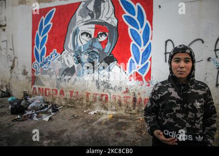 Ein Teenager steht vor einer Wand, auf der eine Zeichnung eines Mannes mit Gasmaske in einem harten Viertel der beliebten Stadt Ettadhamen, einer der bevölkerungsreichsten Städte der Hauptstadt Tunis, aufgraffiert ist. Ettadhamen City, dessen Name „Solidarität“ bedeutet, wurde von den Wellen der internen Migration (Arme, Kleinbauern und Arbeitslose) gebildet, die Tunesien Anfang 1950s kennzeichneten. Die Jugend des Viertels spielte eine zentrale Rolle in der Revolution von 2011, die Präsident Zine el-Abidine Ben Ali stürzte. Seitdem hat sich die Situation verschlechtert: Prekarität, Armut, steigende Lebenshaltungskosten, un Stockfoto