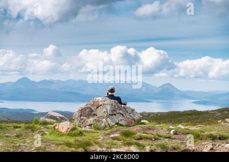 Applecross Peninsula, Highlands of Scotland, UK-Juli 28 2022: Ein Reisender und Wanderer, genießt die Mitte des Sommers Blick, von der Spitze des hohen Gebirgspass, OV Stockfoto