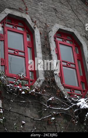 Eine vertikale Aufnahme von schönen traditionellen roten Fenstern an der Fassade eines Gebäudes an einem verschneiten Wintertag Stockfoto