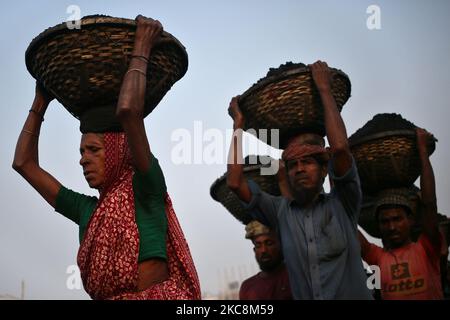 Arbeiter tragen Kohle auf Körben, als sie diese am Mittwoch, den 03. Februar 2021, von einem Frachtschiff am Ufer des Flusses Buriganga in Dhaka, Bangladesch, entladen. (Foto von Syed Mahamudur Rahman/NurPhoto) Stockfoto