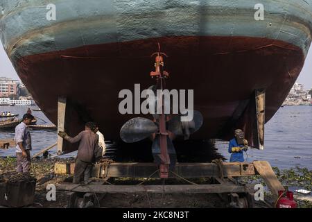 Hafenarbeiter führen am 4. Februar 2021 Wartungsarbeiten am Rumpf eines Schiffes am Ufer des Buriganga-Flusses in Dhaka, Bangladesch, durch. 28 Werften, die 30,96 Hektar des Buriganga-Vorhores besetzen, sind in den letzten 50 Jahren ohne Genehmigung oder Richtlinien in Betrieb, verschmutzen den Fluss und greifen in das Flussufer ein, was seine Schiffbarkeit verringert. (Foto von Ahmed Salahuddin/NurPhoto) Stockfoto