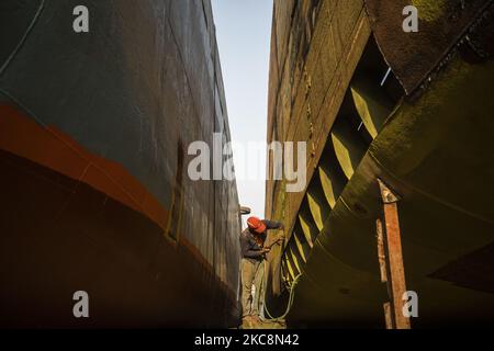 Hafenarbeiter führen am 4. Februar 2021 Wartungsarbeiten am Rumpf eines Schiffes am Ufer des Buriganga-Flusses in Dhaka, Bangladesch, durch. 28 Werften, die 30,96 Hektar des Buriganga-Vorhores besetzen, sind in den letzten 50 Jahren ohne Genehmigung oder Richtlinien in Betrieb, verschmutzen den Fluss und greifen in das Flussufer ein, was seine Schiffbarkeit verringert. (Foto von Ahmed Salahuddin/NurPhoto) Stockfoto