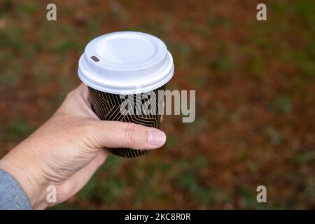 Nahaufnahme der Hände einer Frau, die eine Papiertasse mit Kaffee hält. Stockfoto