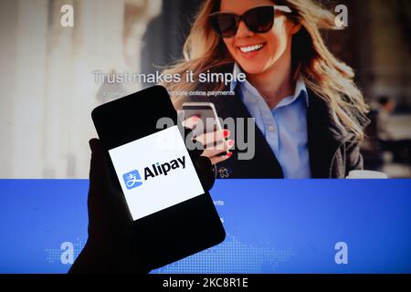 Das Alipay App-Logo wird auf einem Handybildschirm mit Alipay-Website-Hintergrund angezeigt. Krakau, Polen, am 5. Februar 2021. Die chinesische Alipay-App hat mehr als 700 Millionen monatliche Nutzer, die sie verwenden, um zu bezahlen, Kredite aufzunehmen, zu versichern und ihr Geld zu verwalten. (Foto-Illustration von Beata Zawrzel/NurPhoto) Stockfoto