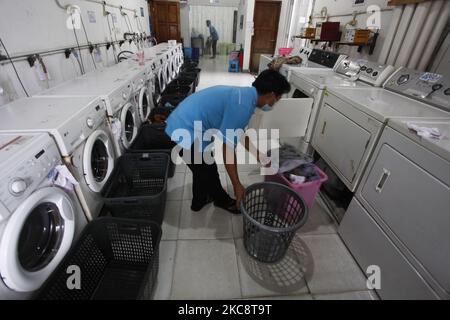 Ein Mitarbeiter lädt am 6. Februar 2021 Wäsche in eine Waschmaschine bei Bogor Laundry in Bogor, West Java. Bogor's Laundry ist ein gewerblicher Wäscheservice für Hotels, Industriebetriebe, Häuser. Die COVID-19-Pandemie hat den Wäschereisektor in der nationalen und globalen Wirtschaft noch nie getroffen. (Foto von Adriana Adie/NurPhoto) Stockfoto