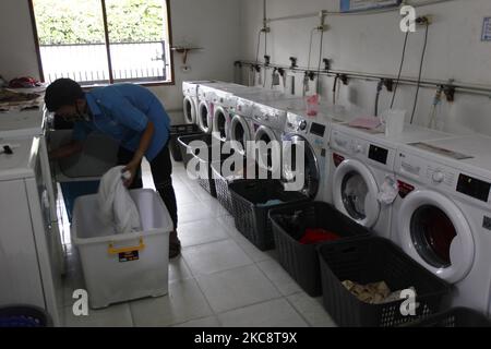 Ein Mitarbeiter lädt am 6. Februar 2021 Wäsche in eine Waschmaschine bei Bogor Laundry in Bogor, West Java. Bogor's Laundry ist ein gewerblicher Wäscheservice für Hotels, Industriebetriebe, Häuser. Die COVID-19-Pandemie hat den Wäschereisektor in der nationalen und globalen Wirtschaft noch nie getroffen. (Foto von Adriana Adie/NurPhoto) Stockfoto