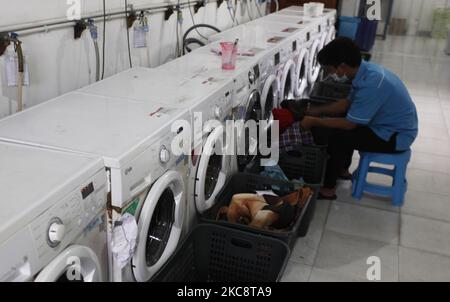 Ein Mitarbeiter lädt am 6. Februar 2021 Wäsche in eine Waschmaschine bei Bogor Laundry in Bogor, West Java. Bogor's Laundry ist ein gewerblicher Wäscheservice für Hotels, Industriebetriebe, Häuser. Die COVID-19-Pandemie hat den Wäschereisektor in der nationalen und globalen Wirtschaft noch nie getroffen. (Foto von Adriana Adie/NurPhoto) Stockfoto