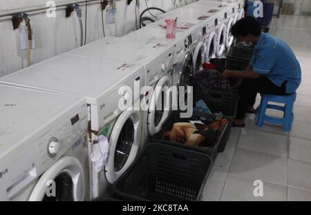 Ein Mitarbeiter lädt am 6. Februar 2021 Wäsche in eine Waschmaschine bei Bogor Laundry in Bogor, West Java. Bogor's Laundry ist ein gewerblicher Wäscheservice für Hotels, Industriebetriebe, Häuser. Die COVID-19-Pandemie hat den Wäschereisektor in der nationalen und globalen Wirtschaft noch nie getroffen. (Foto von Adriana Adie/NurPhoto) Stockfoto