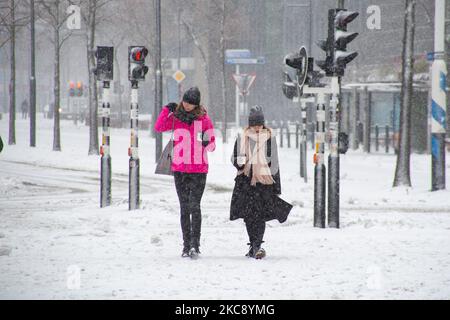 Junge Leute, die eine Tasse Kaffee halten, laufen auf dem Septemberplein 18 in Eindhoven draußen auf dem Schnee. Blizzard vom Schneesturm Darcy in den Niederlanden, dem ersten starken Schneefall mit starken Winden nach 2010, der den Transport im ganzen Land störte. Die Niederländer erwachten am Sonntag mit einer Schneeschicht, die alles bedeckte. Viele Unfälle ereigneten sich auf den Straßen aufgrund des Sturms und der eisigen Bedingungen, während es auch Probleme mit den Zügen gab. In der Stadt Eindhoven in Nordbrabant wurde der Bahn- und Busverkehr eingestellt, der Flughafen folgte und der Luftverkehr umgeleitet. P Stockfoto