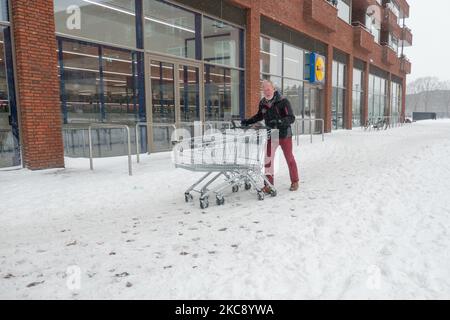 Ein Mann trägt den Supermarktwagen auf dem Schnee. Blizzard vom Schneesturm Darcy in den Niederlanden, dem ersten starken Schneefall mit starken Winden nach 2010, der den Transport im ganzen Land störte. Die Niederländer erwachten am Sonntag mit einer Schneeschicht, die alles bedeckte. Viele Unfälle ereigneten sich auf den Straßen aufgrund des Sturms und der eisigen Bedingungen, während es auch Probleme mit den Zügen gab. In der Stadt Eindhoven in Nordbrabant wurde der Bahn- und Busverkehr eingestellt, der Flughafen folgte und der Luftverkehr umgeleitet. Im Stadtzentrum von Eindhoven ging es nach draußen, um zu enj zu kommen Stockfoto