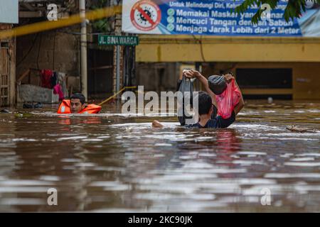 Die Bewohner waten durch ein überflutetes Gebiet, während am 8. Februar 2021 in Süd-Jakarta durch heftige Regenfälle ein Gebiet entlang eines Flusses überflutet wird. (Foto von Afriadi Hikmal/NurPhoto) Stockfoto