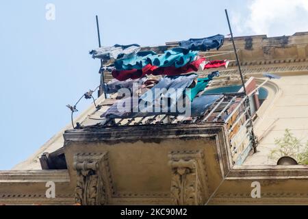 Eine Gruppe von Kleidern trocknet im Wind. Sie hängen an einer Wäscheleine auf einem Balkon eines baufälligen Gebäudes. Stockfoto