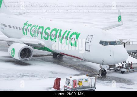 Geerdete Transavia-Flotte, Boeing 737 am Flughafen Eindhoven aufgrund des Schnees. Schneesturm schließt den Flughafen Eindhoven EIN in den Niederlanden. Starker Schneefall stört den Flugverkehr, der am Sonntag zu Umleitungen nach Deutschland führte. Blizzard vom Sturm Darcy traf das Land seit Sonntagmorgen (07.02.2021), was zu Problemen bei den öffentlichen Verkehrsmitteln führte. Auf dem schneebedeckten Flughafen Eindhoven werden Transavia-Flugzeuge am Boden gesehen, während schwere Maschinen die Rollbahn und die Landebahn reinigen. Dutzende von Flügen, die abfliegen sollten, wurden am Flughafen Schiphol in Amsterdam aufgrund der ar verspätet oder gestrichen Stockfoto