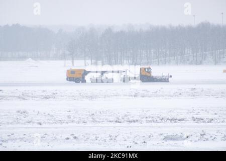 Ein schweres Fahrzeug reinigt die Piste vom Schnee. Schneesturm schließt den Flughafen Eindhoven EIN in den Niederlanden. Starker Schneefall stört den Flugverkehr, der am Sonntag zu Umleitungen nach Deutschland führte. Blizzard vom Sturm Darcy traf das Land seit Sonntagmorgen (07.02.2021), was zu Problemen bei den öffentlichen Verkehrsmitteln führte. Auf dem schneebedeckten Flughafen Eindhoven werden Transavia-Flugzeuge am Boden gesehen, während schwere Maschinen die Rollbahn und die Landebahn reinigen. Dutzende von Flügen, die abfliegen sollten, wurden am Flughafen Schiphol in Amsterdam aufgrund des arktisch kalten Winterweins verspätet oder gestrichen Stockfoto