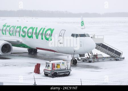 Geerdete Transavia-Flotte, Boeing 737 am Flughafen Eindhoven aufgrund des Schnees. Schneesturm schließt den Flughafen Eindhoven EIN in den Niederlanden. Starker Schneefall stört den Flugverkehr, der am Sonntag zu Umleitungen nach Deutschland führte. Blizzard vom Sturm Darcy traf das Land seit Sonntagmorgen (07.02.2021), was zu Problemen bei den öffentlichen Verkehrsmitteln führte. Auf dem schneebedeckten Flughafen Eindhoven werden Transavia-Flugzeuge am Boden gesehen, während schwere Maschinen die Rollbahn und die Landebahn reinigen. Dutzende von Flügen, die abfliegen sollten, wurden am Flughafen Schiphol in Amsterdam aufgrund der ar verspätet oder gestrichen Stockfoto