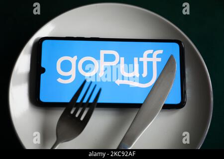 Das GoPuff App-Logo wird auf einem Handybildschirm angezeigt, der zur Illustration auf einem Teller und mit Besteck fotografiert wurde. Krakau, Polen, am 9. Februar 2021. Zahlen zeigen, dass die Covid-19-Pandemie zu einer signifikanten Zunahme der über Apps und Websites bestellten Mahlzeiten führte. (Foto-Illustration von Beata Zawrzel/NurPhoto) Stockfoto