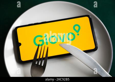 Das Logo der Glovo App wird auf einem Handybildschirm angezeigt, der zur Illustration auf einem Teller und mit Besteck fotografiert wurde. Krakau, Polen, am 9. Februar 2021. Zahlen zeigen, dass die Covid-19-Pandemie zu einer signifikanten Zunahme der über Apps und Websites bestellten Mahlzeiten führte. (Foto-Illustration von Beata Zawrzel/NurPhoto) Stockfoto