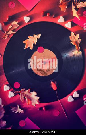 Vintage Vinyl Schallplatten in Papierärmel auf schwarzem Hintergrund und Papierärmel. Gelbe Eichenblätter auf rotem Hintergrund mit Herbstverzierungen. Zucker Stockfoto