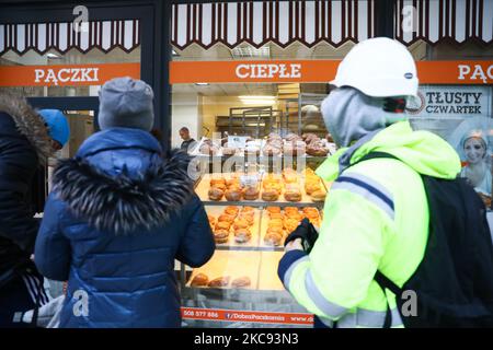 In der Bäckerei „Dobra Paczkarnia“ stehen die Leute am Fat Thursday Schlange, um Donuts zu kaufen. Krakau, Polen am 11. Januar 2021. Fat Thursday ist ein traditionelles katholisches christliches Fest am letzten Donnerstag vor der Fastenzeit. Es symbolisiert die Feier des Karnevals. Das beliebteste Gericht, das an diesem Tag in Polen serviert wird, sind Paczki - faustgroße Donuts, gefüllt mit Marmelade. (Foto von Beata Zawrzel/NurPhoto) Stockfoto