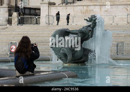 Eine Frau macht am 12. Februar 2021 in London, England, ein Foto einer gefrorenen Meerjungfrau-Statue im Brunnen am Trafalgar Square an einem kalten Wintertag, an dem England noch unter der dritten Sperre steht, um die Covid-19-Infektionsraten zu senken. (Foto von Wiktor Szymanowicz/NurPhoto) Stockfoto