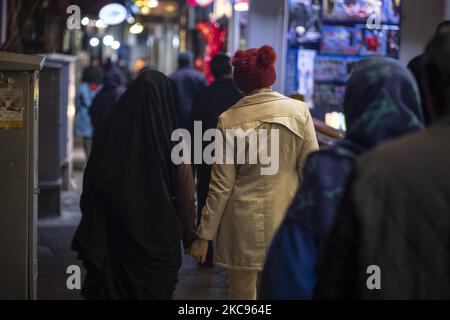 Die iranische verschleierte Frau (L) geht Hand in Hand mit ihrer weiblichen Verwandten entlang einer Straße, während sie am Valentinstag in der Innenstadt von Teheran während des Ausbruchs der COVID-19 im Iran am 12. Februar 2021 einkaufen geht. (Foto von Morteza Nikoubazl/NurPhoto) Stockfoto