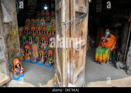 Eine Dame, die eine Maske trägt, sitzt neben den Idolen der Göttin Kaswati und wartet auf Kunden vor der Kaswati Puja , in Kalkutta, Indien, am 13. Februar 2021. Töpfer von Kumartuli sind damit beschäftigt, den Idolen von Devi sarswati vor der Puja von Saliswati am 16.. Februar letzte Feinheiten zu geben. Devi ist bekannt als die hinduistische Göttin des Wissens und der Weisheit, jedes Jahr beten Hindus und Studenten aller Religionen die Göttin an und beten zu ihr, um einem gutes Wissen zu bringen. (Foto von Debarchan Chatterjee/NurPhoto) Stockfoto