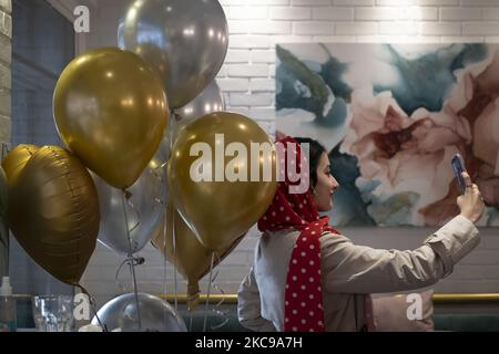 Eine iranische Frau nimmt am Valentinstag in der Innenstadt von Teheran ein Selfie mit Ballons in einem Café auf, während der COVID-19-Ausbruch im Iran am 14. Februar 2021 stattfand. Die iranische Regierung hat die Verwendung der roten Farbe und der Valentinstag-Symbole in Cafés und öffentlichen Bereichen verboten, sagte Ein Café-Mann dem Fotografen. (Foto von Morteza Nikoubazl/NurPhoto) Stockfoto