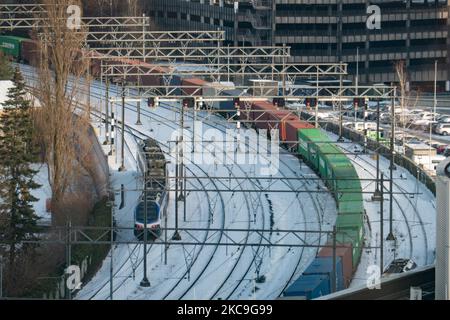 Eine Ladung und ein Personenzug auf den schneebedeckten Schienen im Stadtzentrum. Panorama-Übersicht über die schneebedeckte niederländische Stadt Eindhoven, wie sie im Zentrum und in den Wohngebieten zu sehen ist, während der Schnee über einen Zeitraum von mehr als einer Woche die Straßen, die Eisenbahn und die Dächer bedeckte, wodurch auch Seen und Kanäle gefrieren konnten. Eindhoven, Niederlande am 2021. Februar (Foto: Nicolas Economou/NurPhoto) Stockfoto
