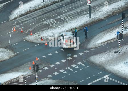 Ein Polizeiauto schließt die Straße, da der Schnee vom Philips PSV-Stadion schnell auf die Straße fällt. Panorama-Übersicht über die schneebedeckte niederländische Stadt Eindhoven, wie sie im Zentrum und in den Wohngebieten zu sehen ist, während der Schnee über einen Zeitraum von mehr als einer Woche die Straßen, die Eisenbahn und die Dächer bedeckte, wodurch auch Seen und Kanäle gefrieren konnten. Eindhoven, Niederlande am 2021. Februar (Foto: Nicolas Economou/NurPhoto) Stockfoto