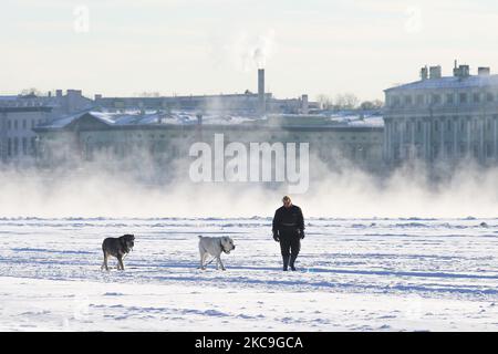 Eine Frau mit Hunden geht am 18. Februar 2021 am gefrorenen Fluss Neva in St. Petersburg, Russland, spazieren. Die Lufttemperatur sank auf -27 Grad. (Foto von Valya Egorshin/NurPhoto) Stockfoto