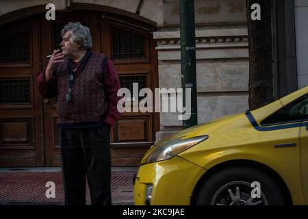 Ein griechischer Taxifahrer, der eine Zigarettenpause hatte. Die Sperrregeln erlauben nur einem Passagier im Taxi, und sowohl Passagier als auch Fahrer müssen am 18. Februar 2021 in Athen, Griechenland, maks tragen. (Foto von Maria Chourdari/NurPhoto) Stockfoto