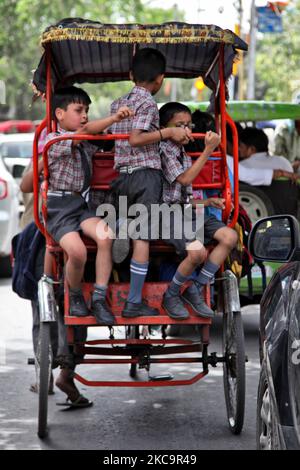 Schulkinder reisen in einer überflutete Rikscha entlang einer belebten Straße auf dem Chandni Chowk Market in Alt-Delhi, Indien. Chandni Chowk ist Asiens größter Großhandelsmarkt. Die Legende besagt, dass der Moghul-Kaiser Shah Jahan Chandni Chowk im 17.. Jahrhundert plante, damit seine Tochter alles kaufen konnte, was sie wollte. Chandni Chowk, also ein mondlichter Platz oder Markt, bleibt eine der belebtesten, chaotischsten und berühmtesten Gegenden der Stadt. (Foto von Creative Touch Imaging Ltd./NurPhoto) Stockfoto