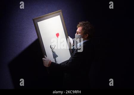 Ein Mitarbeiter der Galerie posiert mit „Girl with Balloon“, 2004, von Banksy (est. £100.000-150.000) während eines Fotoanrufs für Bonhams' Briten. Cool. Am 22. Februar 2021 in London, England, wird ein vielfältiges Angebot britischer und emigrierter Talente aus den letzten hundert Jahren präsentiert. (Foto von Wiktor Szymanowicz/NurPhoto) Stockfoto