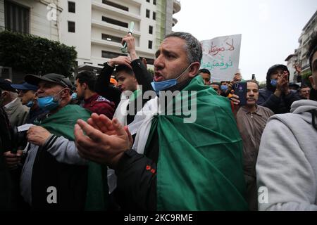 Algerier halten eine Nationalflagge mit der arabischen Inschrift, die die Erwähnung trägt, während sie zum zweiten Jahrestag der Volksproteste in Algier, Algerien, am 22. Februar 2021 marschieren. Algerien feiert den zweiten Jahrestag der Bewegung am 22. Februar 2021 Massenprotest, bekannt als Hirak, der zum Rücktritt des damaligen Präsidenten Abdelaziz Bouteflika führte. Der amtierende algerische Präsident Abdelmadjid Tebbounne kündigte am 18. Februar die Begnadigung und Freilassung von etwa sechzig Personen an, die aufgrund ihrer Beteiligung an der Hirak-Protestbewegung verurteilt oder auf ein Gerichtsverfahren warten. Er sagte auch, dass er es war Stockfoto