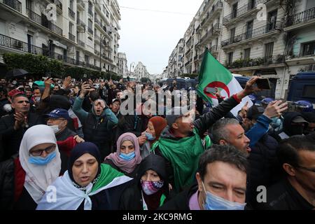 Algerier halten eine Nationalflagge mit der arabischen Inschrift, die die Erwähnung trägt, während sie zum zweiten Jahrestag der Volksproteste in Algier, Algerien, am 22. Februar 2021 marschieren. Algerien feiert den zweiten Jahrestag der Bewegung am 22. Februar 2021 Massenprotest, bekannt als Hirak, der zum Rücktritt des damaligen Präsidenten Abdelaziz Bouteflika führte. Der amtierende algerische Präsident Abdelmadjid Tebbounne kündigte am 18. Februar die Begnadigung und Freilassung von etwa sechzig Personen an, die aufgrund ihrer Beteiligung an der Hirak-Protestbewegung verurteilt oder auf ein Gerichtsverfahren warten. Er sagte auch, dass er es war Stockfoto