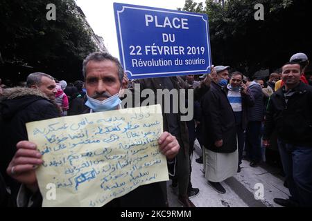 Algerier halten eine Nationalflagge mit der arabischen Inschrift, die die Erwähnung trägt, während sie zum zweiten Jahrestag der Volksproteste in Algier, Algerien, am 22. Februar 2021 marschieren. Algerien feiert den zweiten Jahrestag der Bewegung am 22. Februar 2021 Massenprotest, bekannt als Hirak, der zum Rücktritt des damaligen Präsidenten Abdelaziz Bouteflika führte. Der amtierende algerische Präsident Abdelmadjid Tebbounne kündigte am 18. Februar die Begnadigung und Freilassung von etwa sechzig Personen an, die aufgrund ihrer Beteiligung an der Hirak-Protestbewegung verurteilt oder auf ein Gerichtsverfahren warten. Er sagte auch, dass er es war Stockfoto