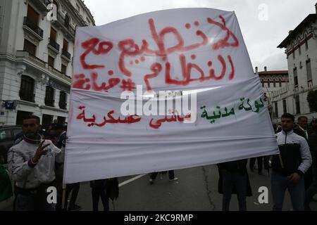 Algerier halten eine Nationalflagge mit der arabischen Inschrift, die die Erwähnung trägt, während sie zum zweiten Jahrestag der Volksproteste in Algier, Algerien, am 22. Februar 2021 marschieren. Algerien feiert den zweiten Jahrestag der Bewegung am 22. Februar 2021 Massenprotest, bekannt als Hirak, der zum Rücktritt des damaligen Präsidenten Abdelaziz Bouteflika führte. Der amtierende algerische Präsident Abdelmadjid Tebbounne kündigte am 18. Februar die Begnadigung und Freilassung von etwa sechzig Personen an, die aufgrund ihrer Beteiligung an der Hirak-Protestbewegung verurteilt oder auf ein Gerichtsverfahren warten. Er sagte auch, dass er es war Stockfoto