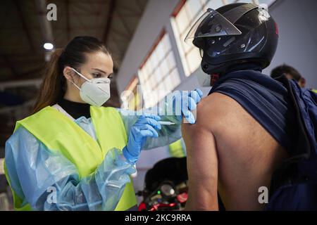 Ein Gesundheitsmitarbeiter mit Handschuhen verabreicht einem Mann in seinem Motorrad während der Impfung von Lehrern und Lehrern in den Armilla-Messepavillons am 22. Februar 2021 in Armilla (Granada, Spanien) den Impfstoff AstraZeneca Covid-19. Die andalusische Regionalregierung beginnt mit der Impfung gegen Covid-19 mit Impfstoffen von AstraZeneca, die in den 10.000 Bildungsfachkräften und Lehrern im Bezirk Granada zentralisiert werden. (Foto von Fermin Rodriguez/NurPhoto) Stockfoto